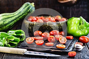 Sliced Ã¢â¬â¹Ã¢â¬â¹red tomato to be used as a culinary ingredient on rustic wooden cutting board, vegan and organic cuisine photo